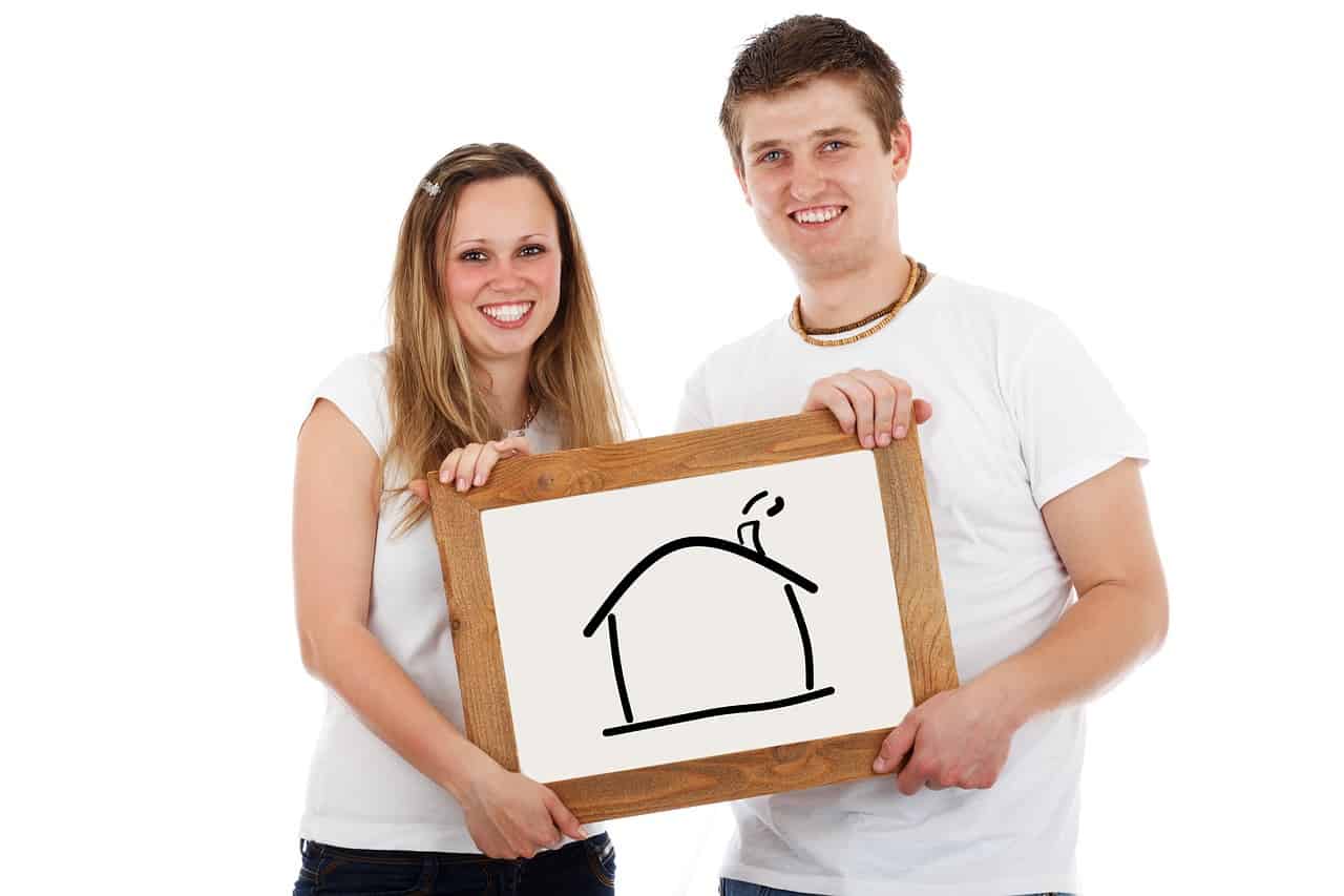 זוג מחזיק שלט עם תמונה של בית